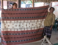The leader of Grupa Feto Fitun Fronteira (left) displays a full-sized tais that takes a month to weave and sells for US$150.